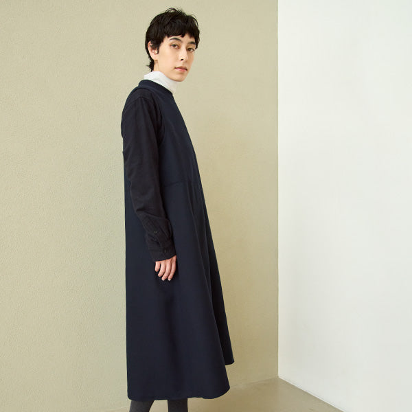 Person wearing a long dress against a plain background