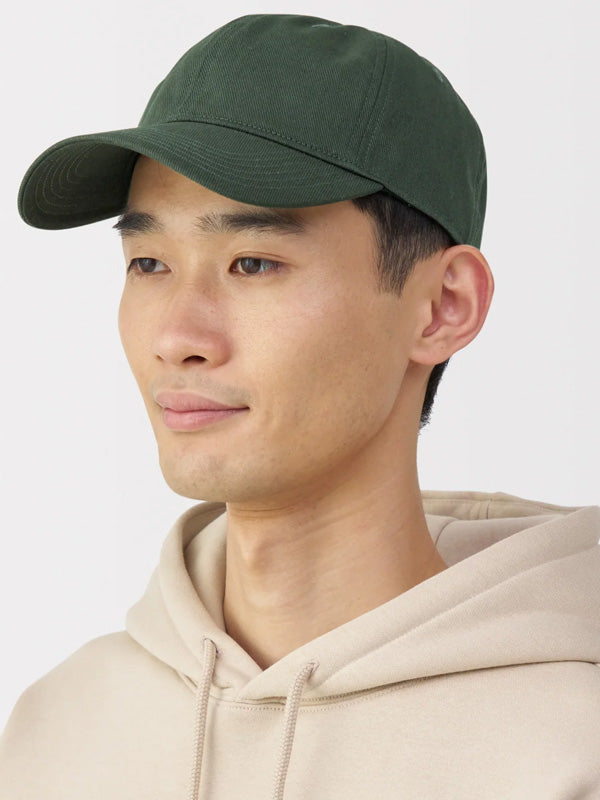 Person wearing a green cap and beige hoodie against a white background