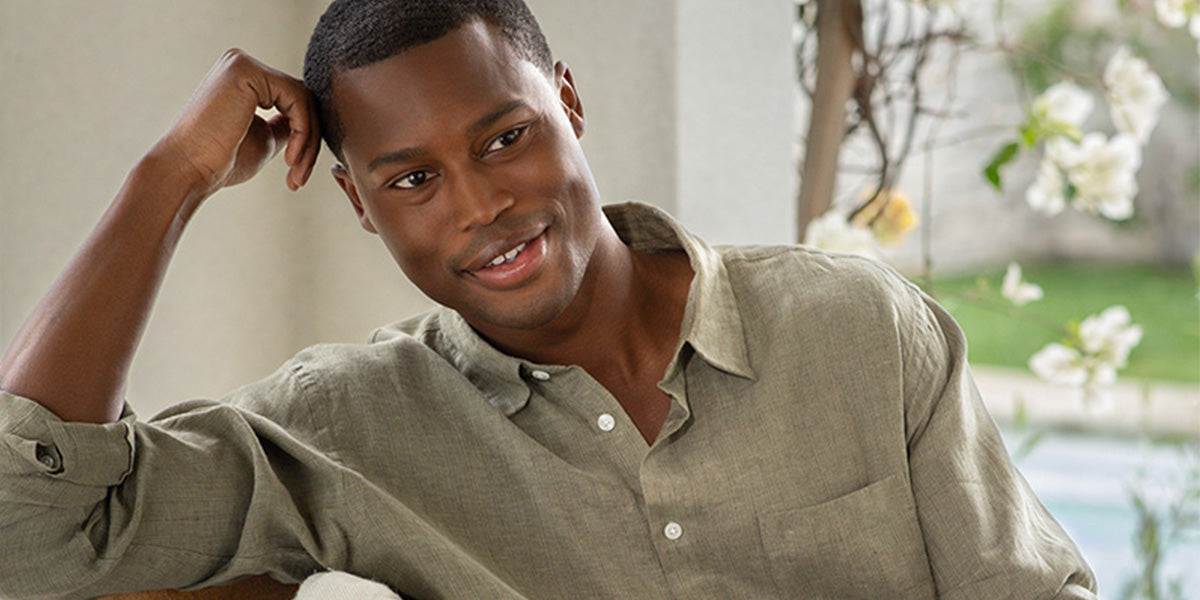 Man in a green shirt sitting outdoors with a blurred background