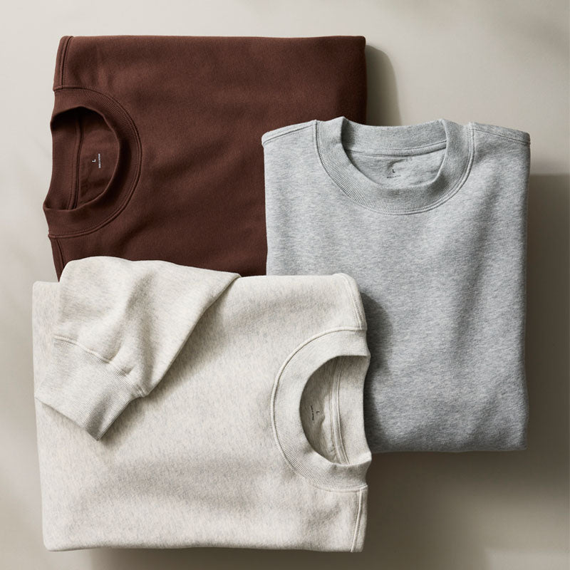 Three folded crewneck sweatshirts arranged in an overlapping flat lay.